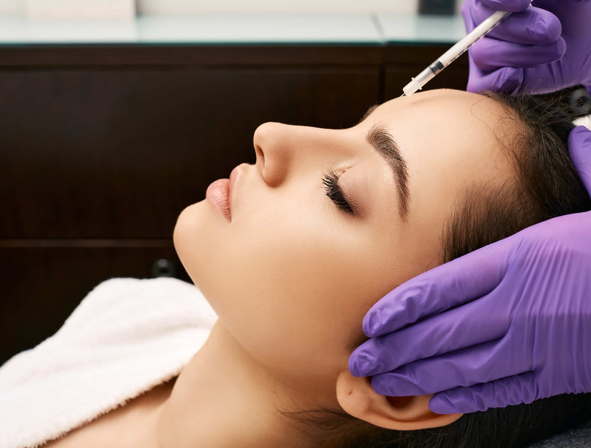 Close-up of a Botox injection being administered near the brow
